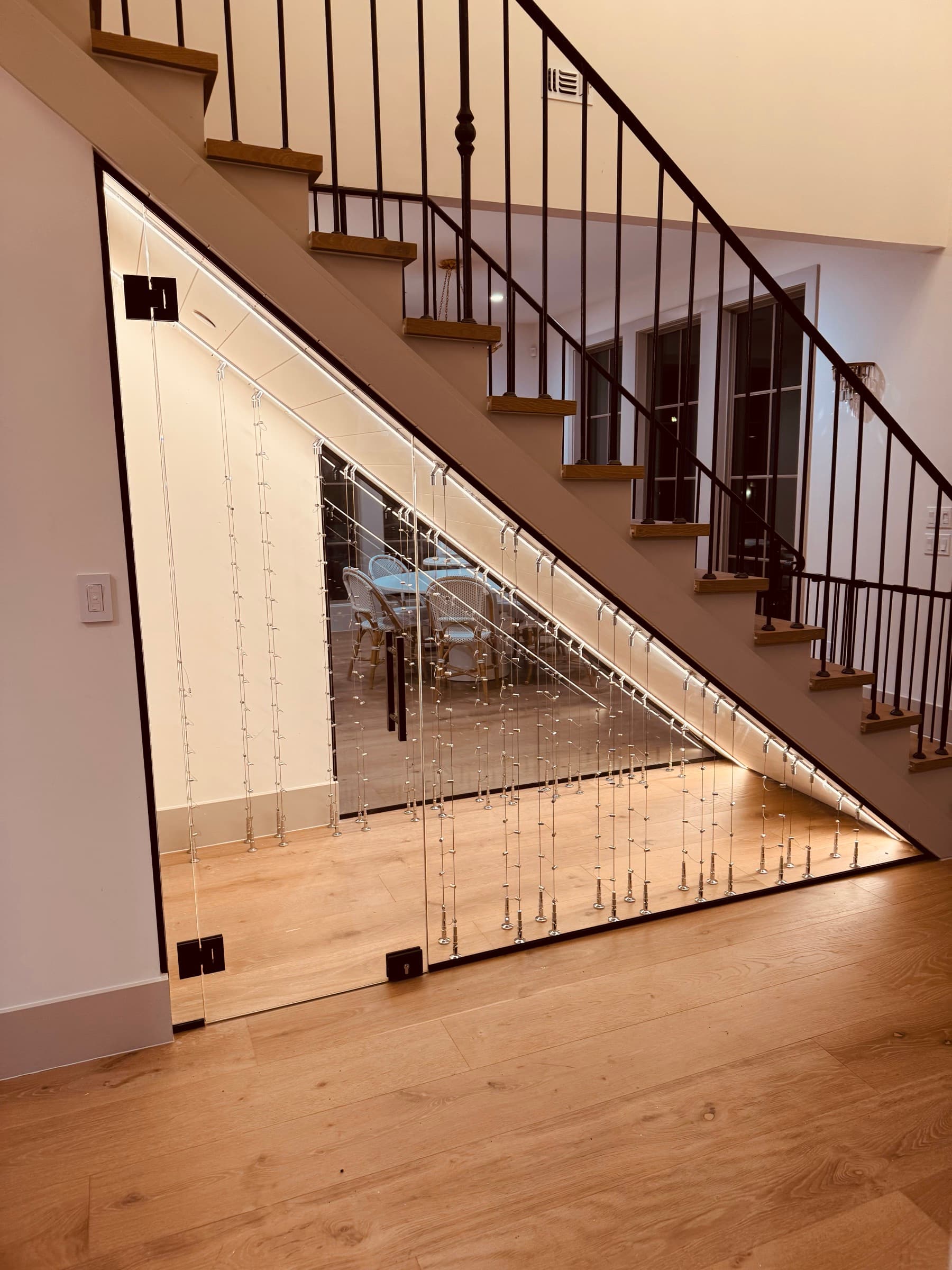 The same space after Bijou installed polished chrome cable racks behind frameless Starphire glass. The passive wine cellar taking shape