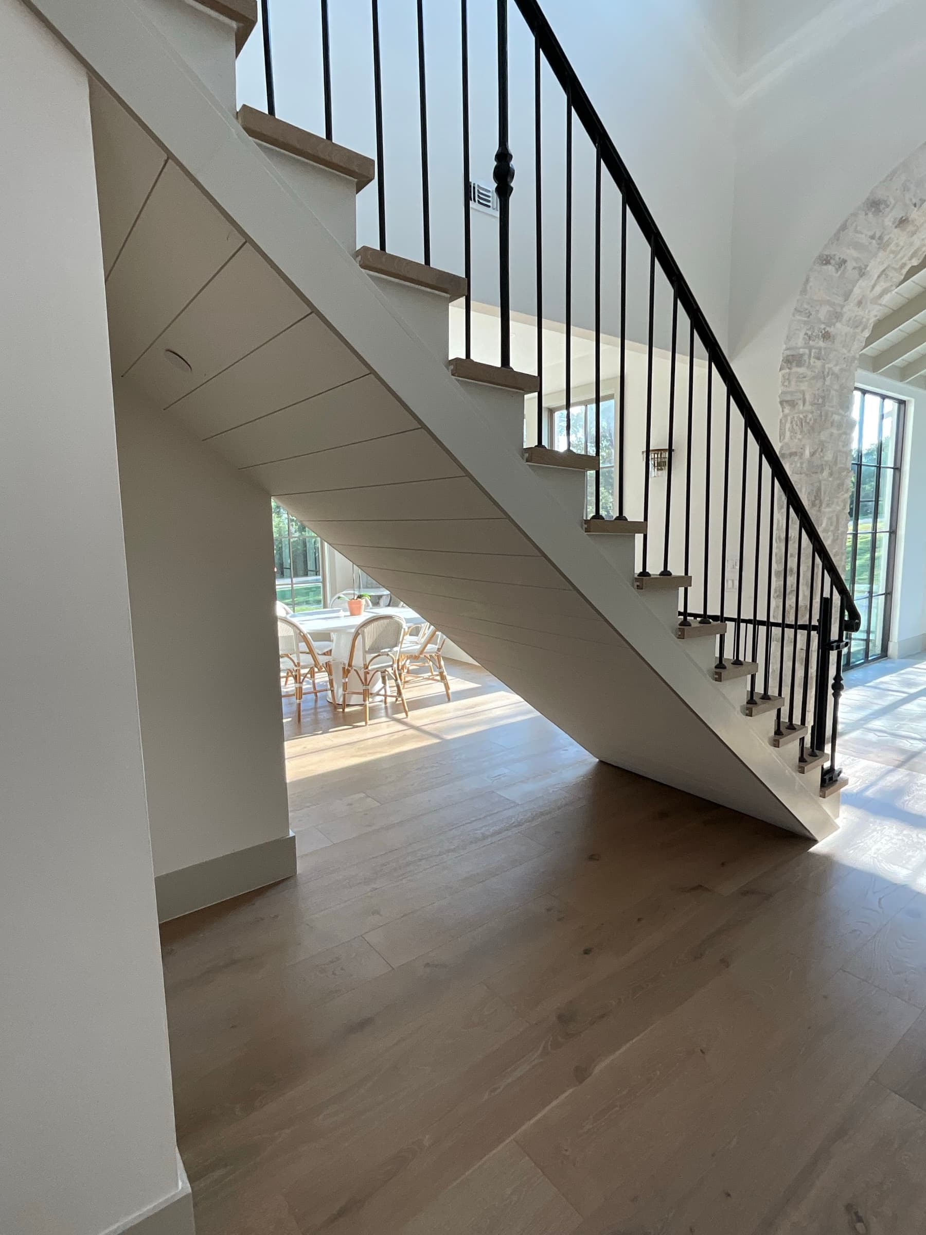 The space under the grand staircase before the wine cellar was built. Empty drywall and dead space beneath iron balusters and wood treads