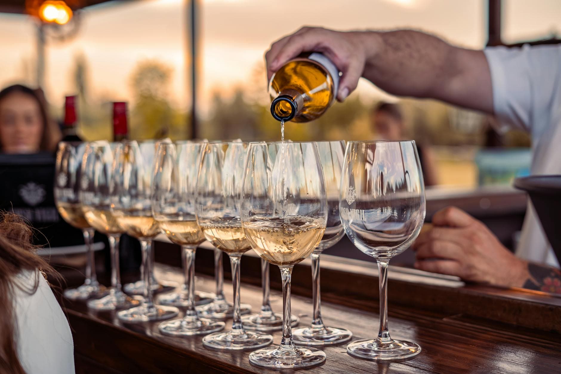 A flight of wine glasses on a bar counter, showing different wine colors from white to deep red