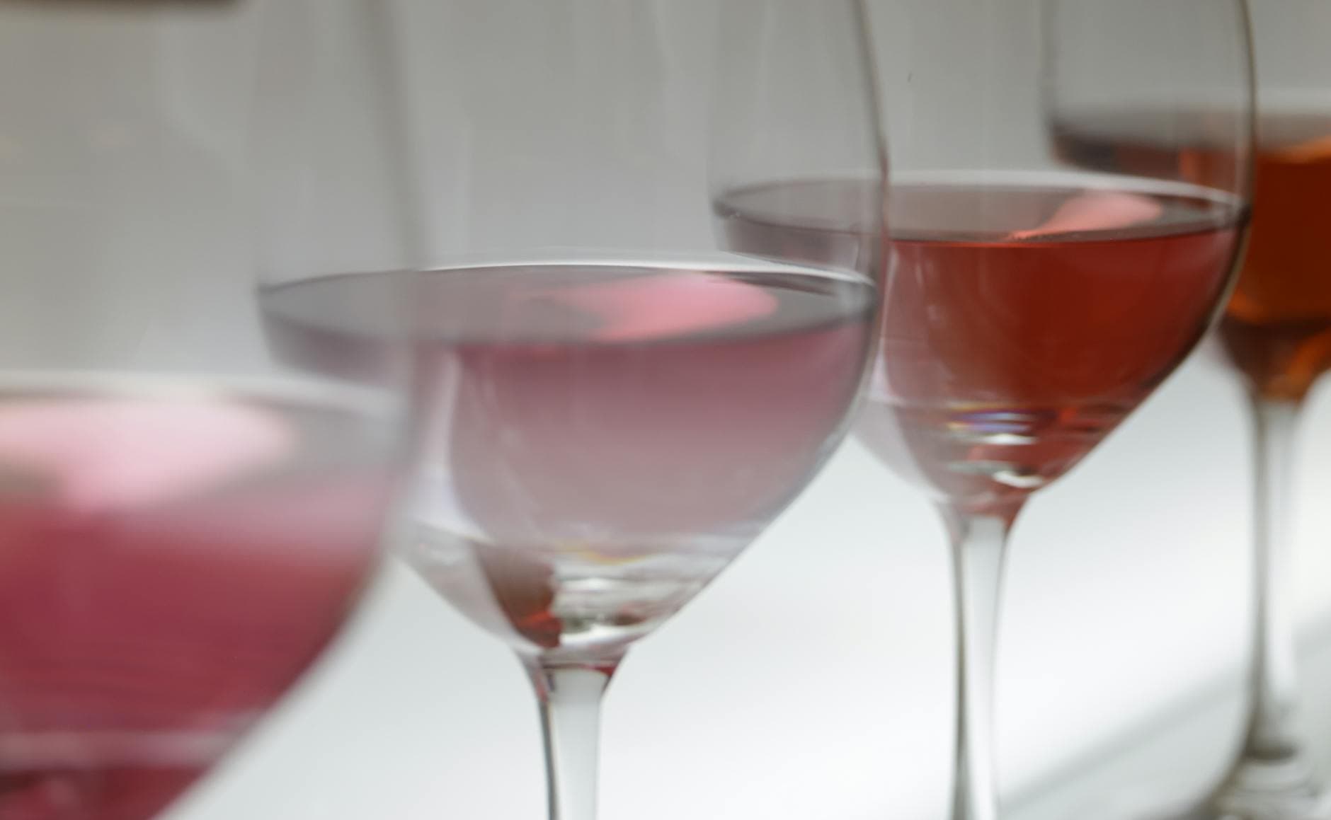 A tasting flight of wines in stemmed glasses, showing varied colors from pale straw to deep red