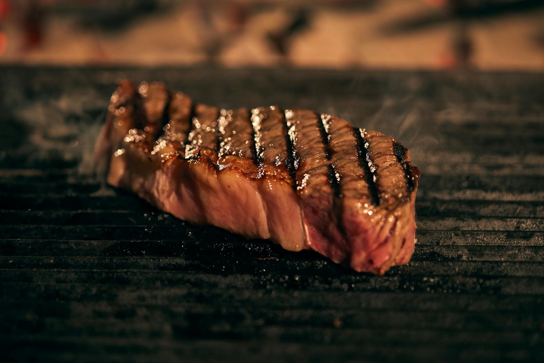 A close-up of a perfectly grilled ribeye steak with grill marks and a charred crust